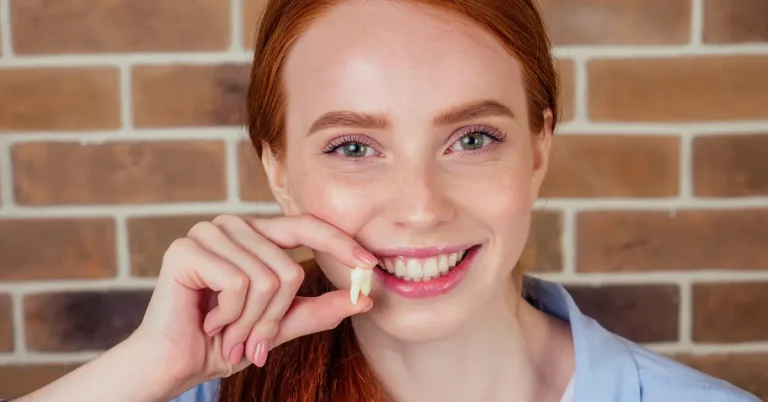What Patients Wish They Knew Before Getting Their Wisdom Teeth Removed - Smiling young woman holding a removed wisdom tooth after dental extraction.